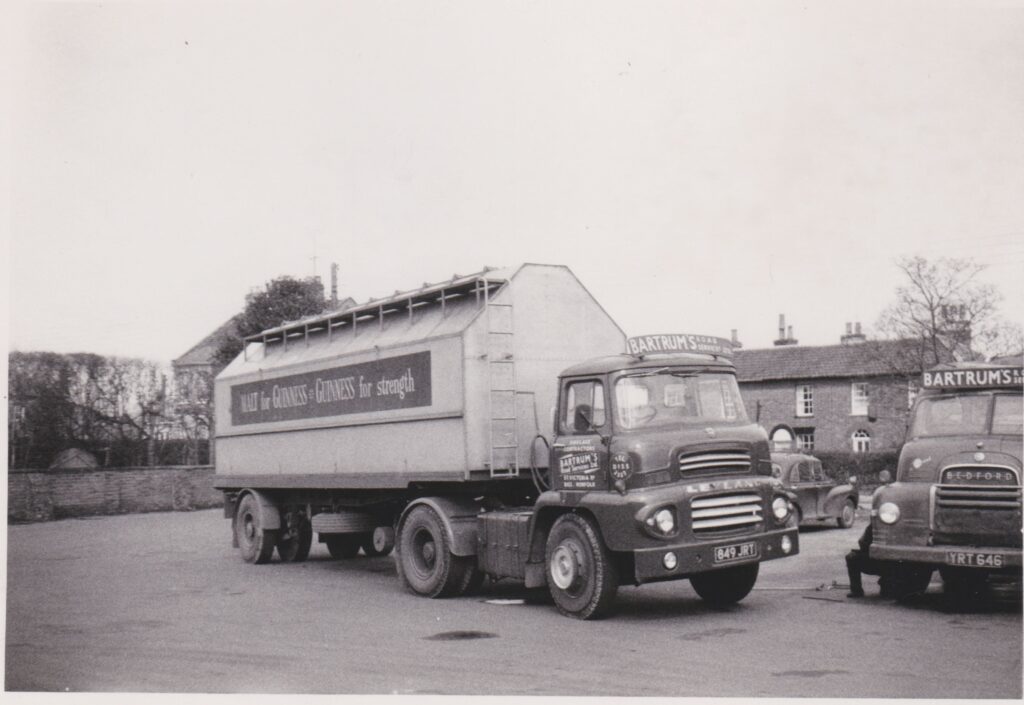 A black and white photograph of an old bulk lorry vehicle. Branding for Guinness is on the side.