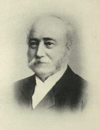 A faded black and white photograph of a light-skinned man with a large moustache.