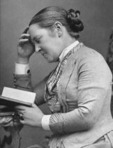 A black and white photograph of a woman reading.