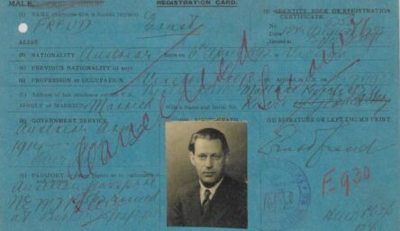 An old blue postcard size document with faded black and red handwriting, and a passport image of a man dressed in a suit and tie.