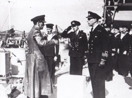 A black and white photo of naval officers saluting.
