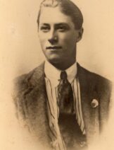 Sepia toned photo of a white man in a suit. The edges of his images are faded.