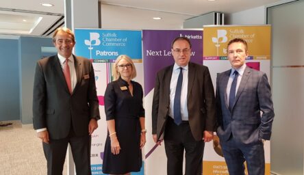 A group of three white men and a white woman standing in front of banner stands