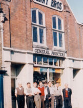 A coloured photograph of people outside a shopfront.