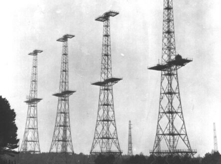 A black and white photograph of four tall radio towers.