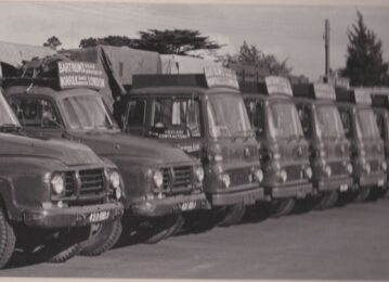 A black and white photograph of a row of old lorries.